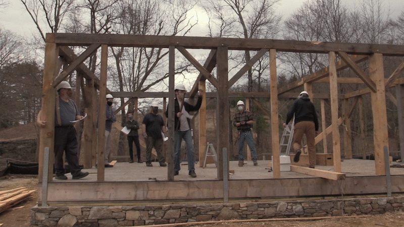 A Village staff member smashes a bottle of apple wine on a timber frame of the Cabinemtaking shop