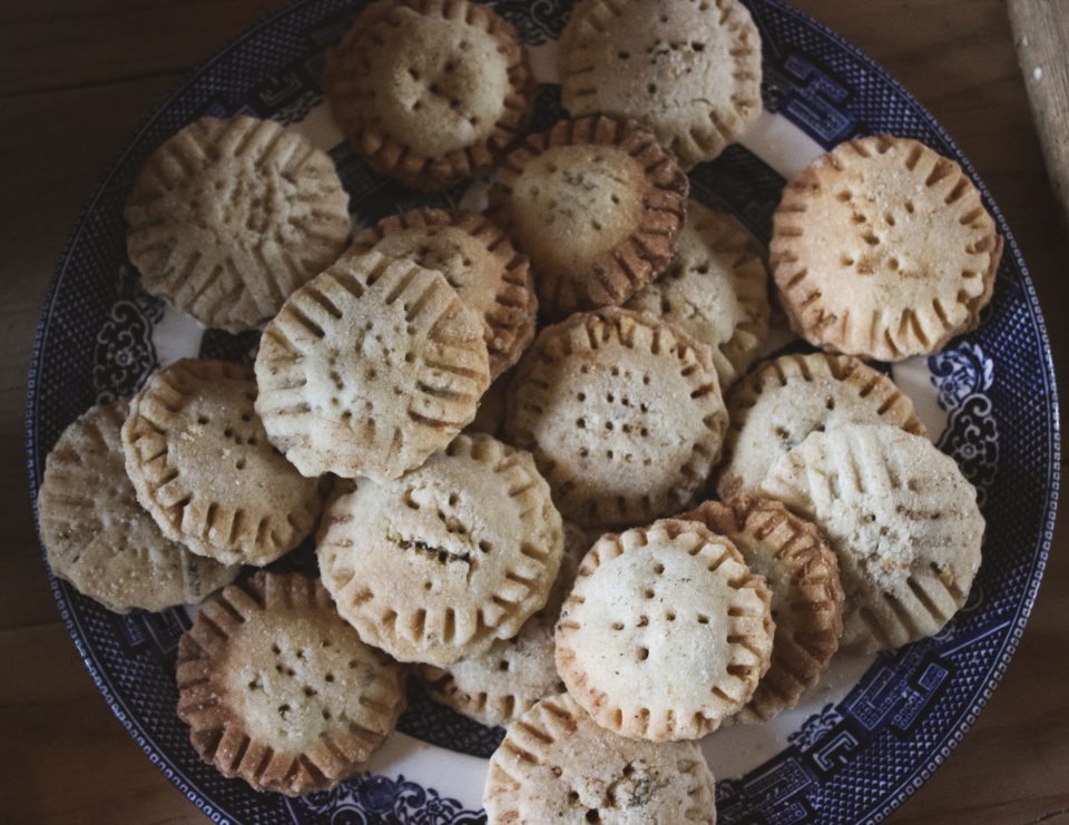 A couple dozen mince pie cookies on a blue and white plate