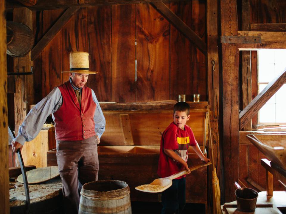 A boy and a costumed historian in the Grist Mill