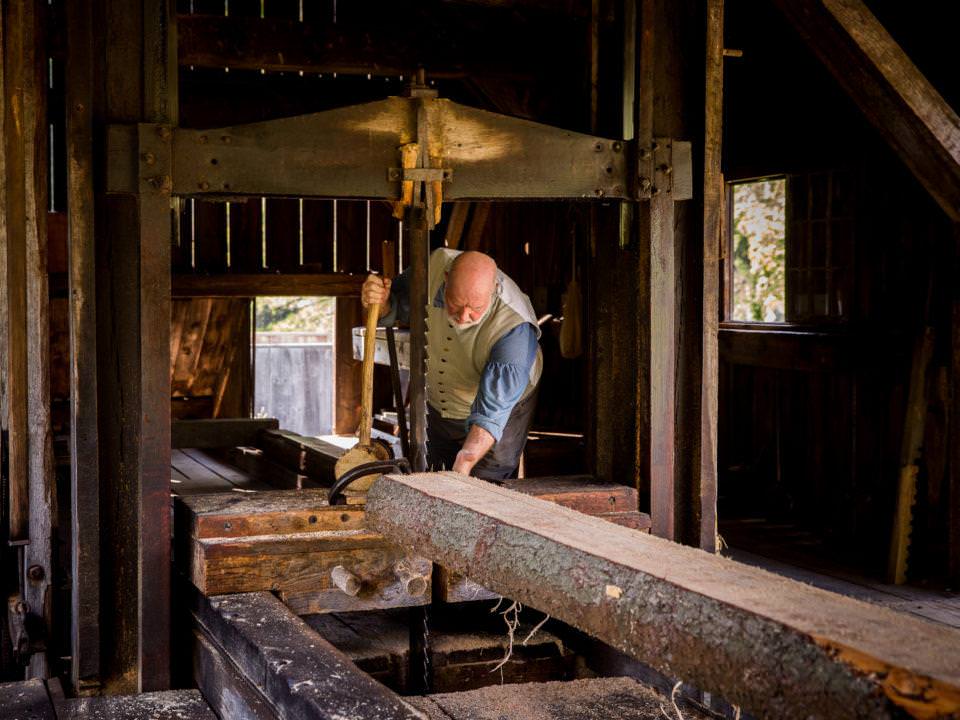 A costumed historian works in the Sawmill