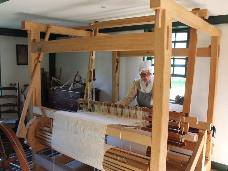 A costumed Historian Weaving in the Fenno House