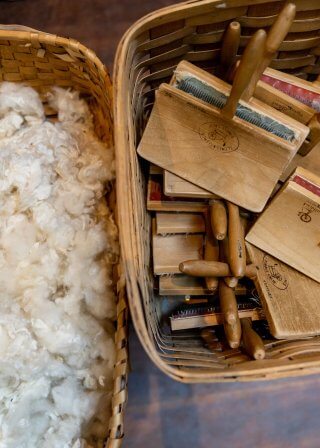 Two baskets, one with wool and one with carding brushes