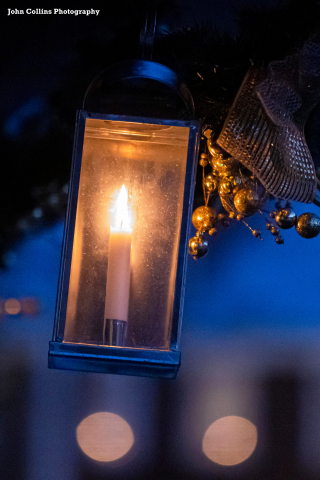 A tin and glass lantern with a candle lit inside
